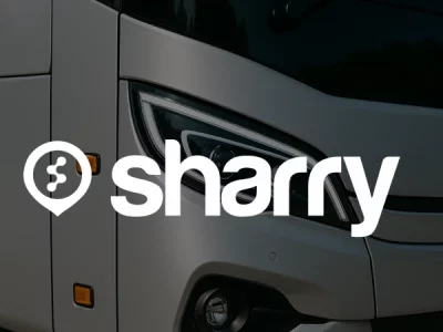 логотип і назва компанії Sharry на фоні фари сірого автобуса