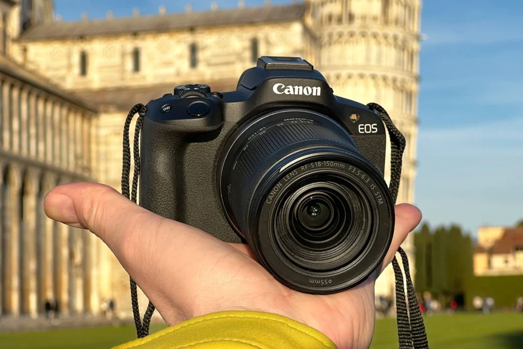 Canon EOS R50 із зумом RF-S 18-150mm f/3.5-6.3 IS STM у руці на тлі Пізанської вежі
